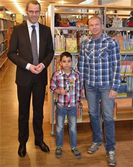 Bürgermeister und Kulturdezernent Dr. Maximilian Ingenthron (l.) überreichte dem jungen Gewinner Amir Kamel im Beisein seines Vaters Miroslaw Fritsche (r.) den Buchscheck und gratulierte ihm zu seinem Erfolg.