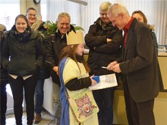 OB Dieter Gummer (r.) übergibt Sternsingerin Luzy Wonder die Spende der Stadt Hockenheim für die diesjährige Aktion Dreikönigssingen